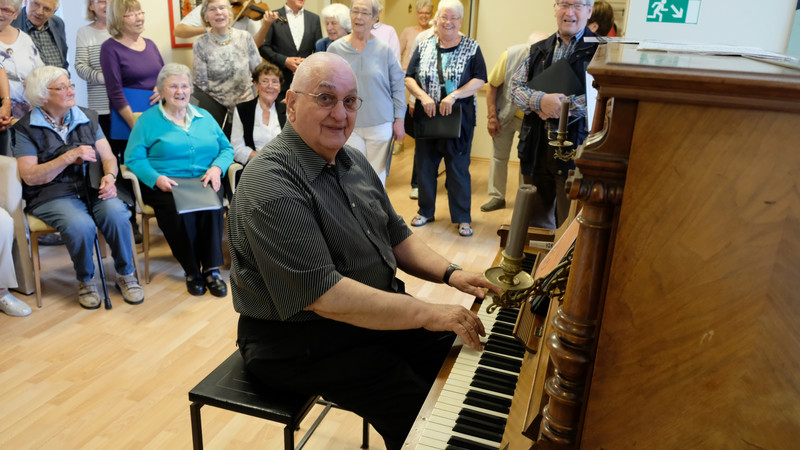 Chorleiter Walter Schulte an dem Klavier, auf dem er regelmäßig für Hospizgäste aufspielt.